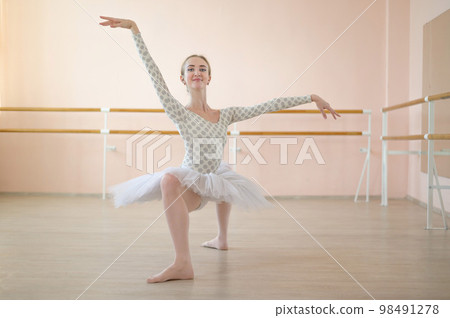 A very flexible ballerina in a tutu stands in a plie in a class with ballet machines. Hypermobility of joints and connective tissue dysplasia. 98491278