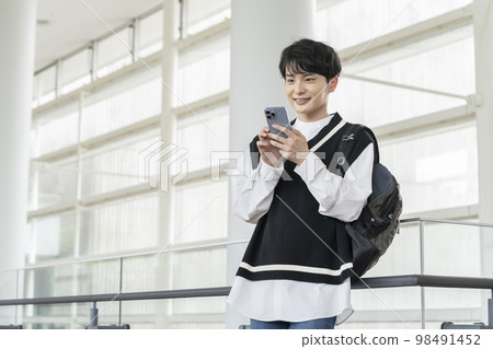 A smiling young man with a smartphone 98491452