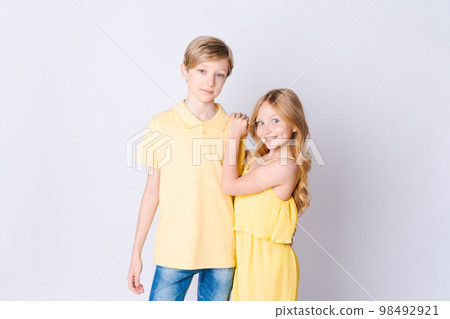 Two happy children standing near an empty gray background and hugging cute 98492921