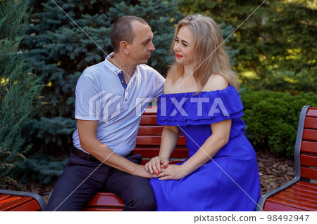 Happy young couple in love sitting on a park bench. Concept of happy family. life style. Happy young couple in love sitting on a park bench. Concept of happy family. life style. 98492947