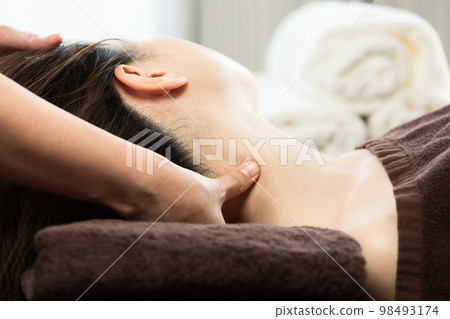 A woman is getting a neck massage. A woman is getting a neck massage. 98493174