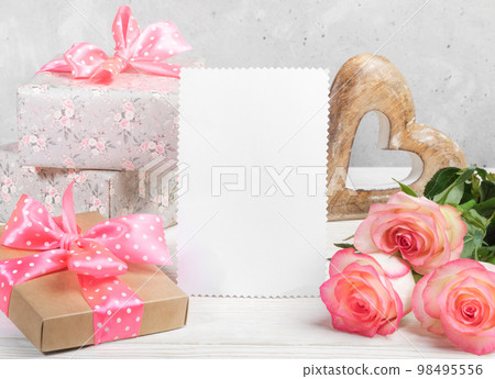 Festive composition with gift boxes, peach color roses, wooden heart, empty white blank for text. Festive composition with gift boxes, peach color roses, wooden heart, empty white blank for text. 98495556