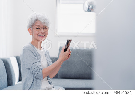微笑著操作智能手機的高級女性 微笑著操作智能手機的高級女性 98495584