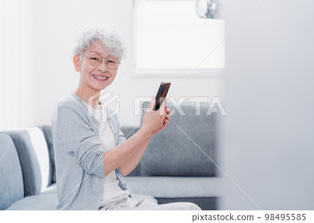 微笑著操作智能手機的高級女性 微笑著操作智能手機的高級女性 98495585