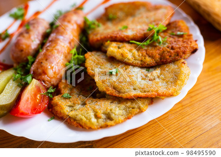 potato pancakes with fried sausages on a white plate potato pancakes with fried sausages on a white plate 98495590