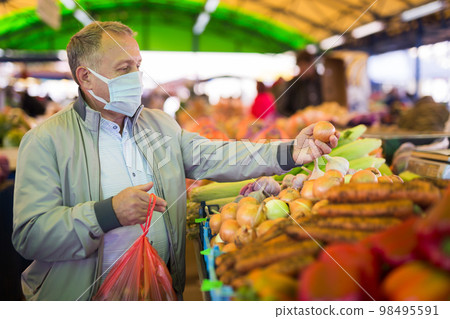 Middle aged man in mask buying onions Middle aged man in mask buying onions 98495591