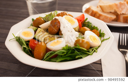 fresh salad of arugula, avocado, cherry tomatoes with olives and quail eggs in white bowl fresh salad of arugula, avocado, cherry tomatoes with olives and quail eggs in white bowl 98495592