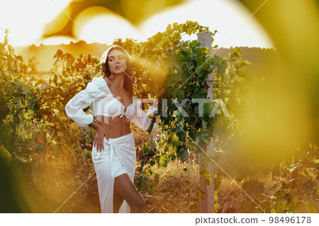 Beautiful young blonde woman walking outdoors in vineyard in summer. 98496178