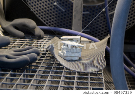 Models printed on a 3D printer from white polyamide powder inside a shot blasting machine for cleaning. Inside Shot blasting machine. Open machine for shot blasting of objects. Industrial machine Models printed on a 3D printer from white polyamide powder inside a shot blasting machine for cleaning. Inside Shot blasting machine. Open machine for shot blasting of objects. Industrial machine 98497339