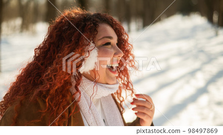 Cheerful fat caucasian woman in fur headphones outdoors. Cheerful fat caucasian woman in fur headphones outdoors. 98497869