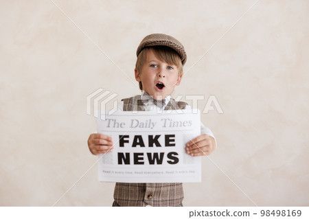 Newsboy shouting against grunge wall background. Boy selling fake news Newsboy shouting against grunge wall background. Boy selling fake news 98498169