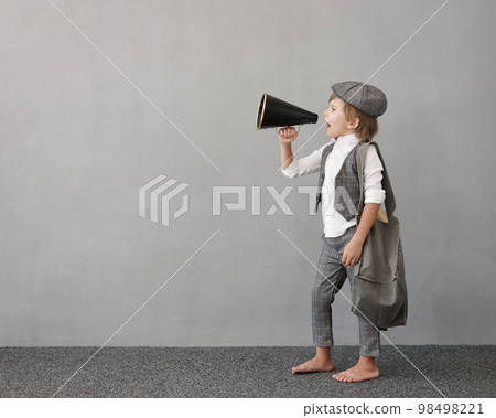 Newsboy shouting against grunge wall background. Boy selling newspaper Newsboy shouting against grunge wall background. Boy selling newspaper 98498221