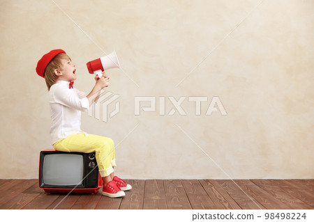 Newsboy shouting against grunge wall background. Boy selling newspaper Newsboy shouting against grunge wall background. Boy selling newspaper 98498224