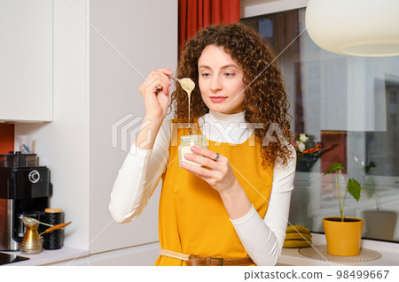Young woman examining texture of sesame seed paste urbech Young woman examining texture of sesame seed paste urbech 98499667