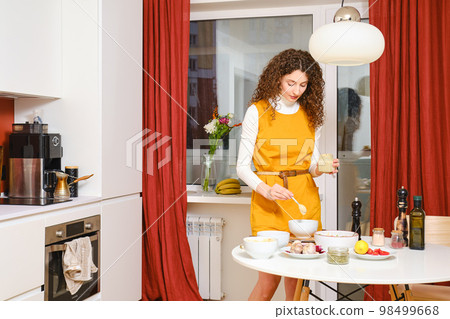Young woman adds sesame seed paste in a bowl with salad Young woman adds sesame seed paste in a bowl with salad 98499668
