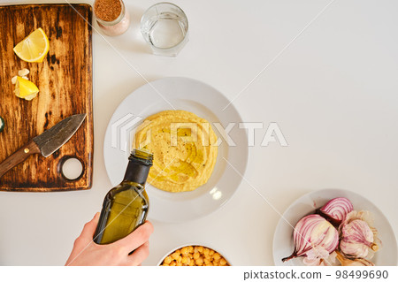Adding olive oil to hummus, view from above 98499690