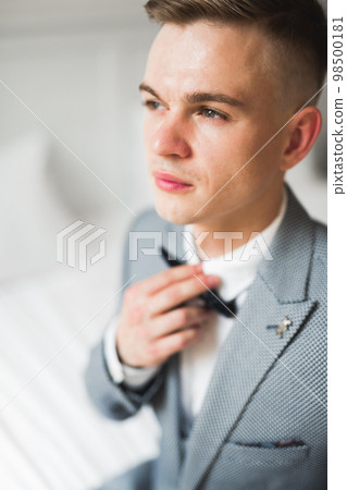 Grooms morning preparation. Handsome man getting dressed and preparing for the wedding Grooms morning preparation. Handsome man getting dressed and preparing for the wedding 98500181
