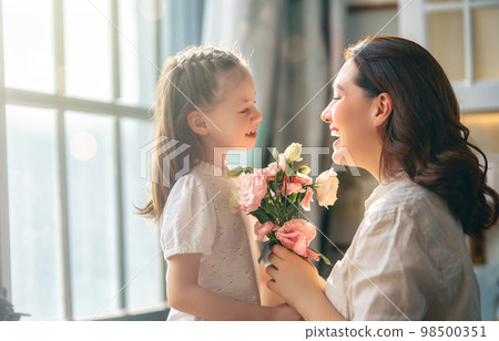 Daughter giving mother bouquet of flowers. 98500351