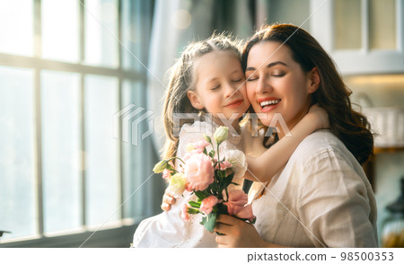Daughter giving mother bouquet of flowers. 98500353