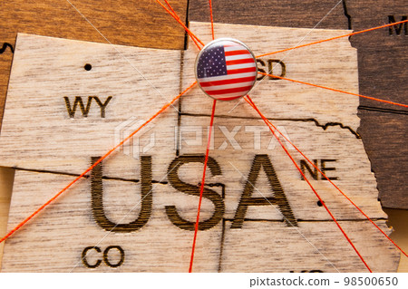 XXX flag on the pushpin with red thread showed the paths of movement or areas of influence in the global economy on the wooden map. Planning of traveling or logistic concept. Network connection.  98500650