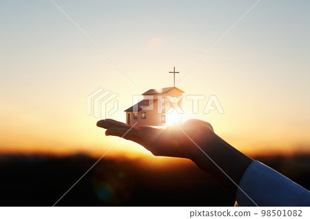 Precious and beautiful temple and church architecture and cross on hand and bright sun sunset background 98501082