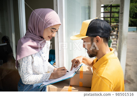 girl in veil signs when delivery man in yellow uniform 98501516