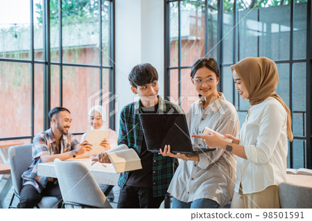 three young people using laptop with cafe as a background 98501591
