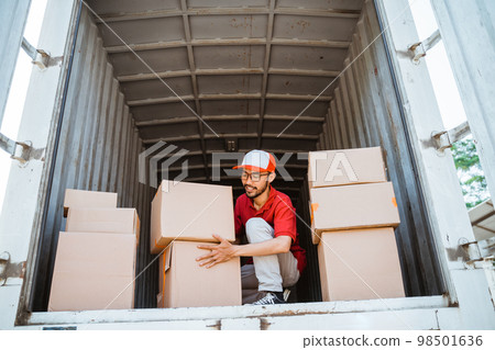 Asian delivery man stacking cardboard boxes of packages 98501636