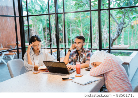 group of sad students using a laptop while working together 98501713