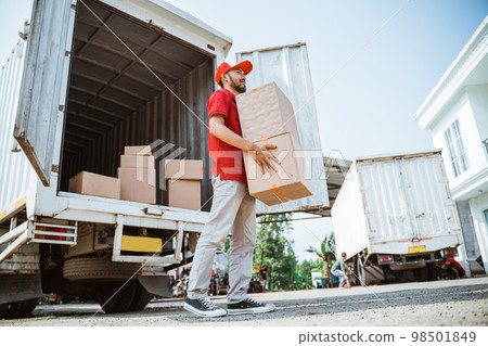 courier man in red uniform lifting parcel box from container 98501849