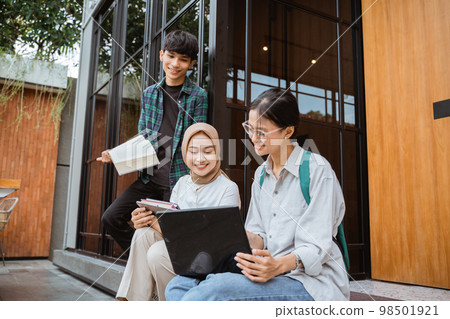 Young college students using laptop for work near glass windows 98501921