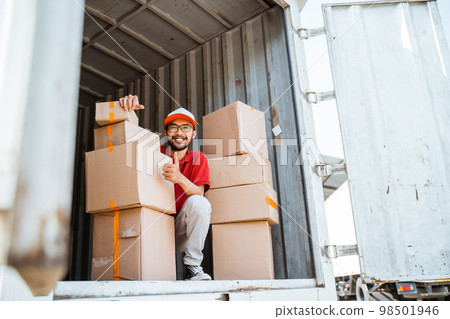 delivery man with thumbs up working unloading boxes from containers 98501946