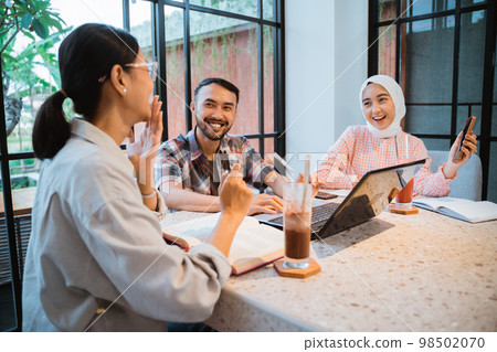 three college students chatting using cellphones and a laptop 98502070