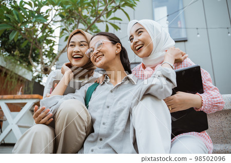 joy of three young asian people smiling while sitting together joy of three young asian people smiling while sitting together 98502096