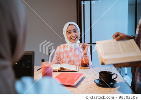 beautiful hijab girl chatting while enjoying drinking with friends beautiful hijab girl chatting while enjoying drinking with friends 98502109