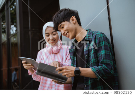a girl and a boy with digital tablet and book 98502150