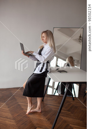 Woman in a white shirt is sitting on the table. Working day. 98502154