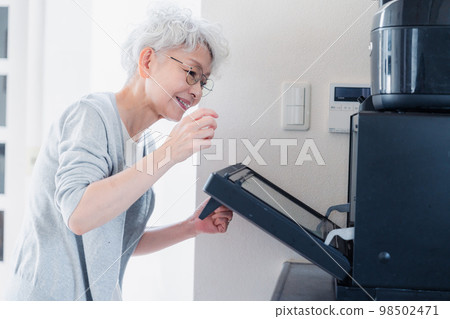 Senior woman warming cup in microwave Senior woman warming cup in microwave 98502471