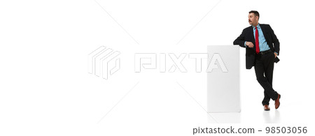 Businessman, employee, manager in a suit leaning on box over white studio background. Banner, flyer. Concept of business, career, innovations, ad Businessman, employee, manager in a suit leaning on box over white studio background. Banner, flyer. Concept of business, career, innovations, ad 98503056