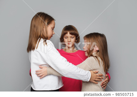 Happy kids embracing on grey background 98503715