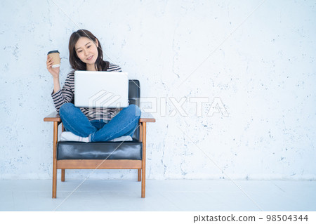 A woman doing remote work in a bright white living room 98504344