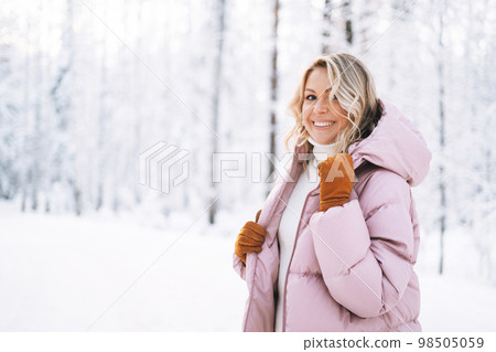 Portrait of smiling woman with blonde hair in winter clothes in snowy winter forest Portrait of smiling woman with blonde hair in winter clothes in snowy winter forest 98505059