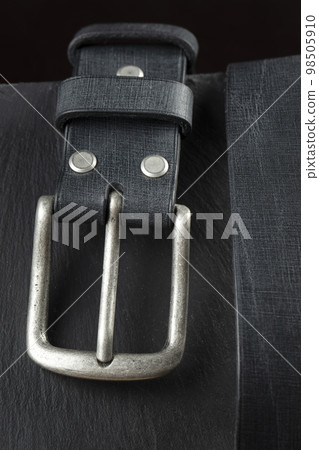 Black leather belt on a dark background. Leather products. Black leather belt on a dark background. Leather products. 98505910