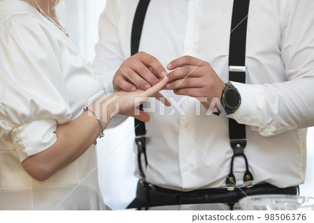 The bride and groom wear wedding rings. The bride and groom wear wedding rings. 98506376