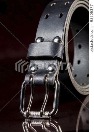 Black leather belt on a dark background. Leather products. Black leather belt on a dark background. Leather products. 98506377