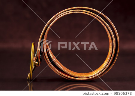 Leather belt twisted on a dark background. Leather belt twisted on a dark background. 98506378
