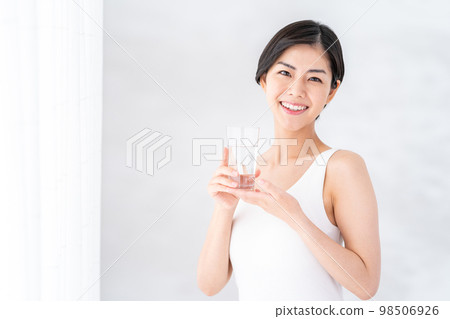 一個女人在窗邊喝水。 一個女人在窗邊喝水。 98506926