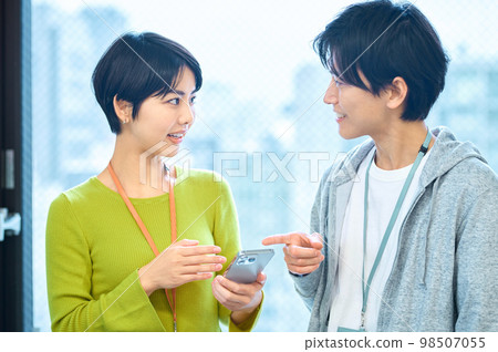 男性和女性 IT 工程師在辦公室看智能手機時進行諮詢 98507055
