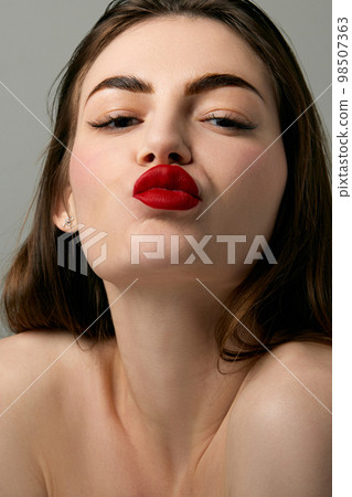 Closeup portrait of beautiful brunette model girl with long straight hair and bright red lipstick on lips. Concept of beauty, fashion, style, emotions Closeup portrait of beautiful brunette model girl with long straight hair and bright red lipstick on lips. Concept of beauty, fashion, style, emotions 98507363