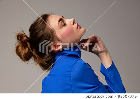 Fashionable stylish emotional woman wearing blue shirt posing over gray background. Model with vivid facial expression. Concept of fashion, style, youth, beauty 98507379